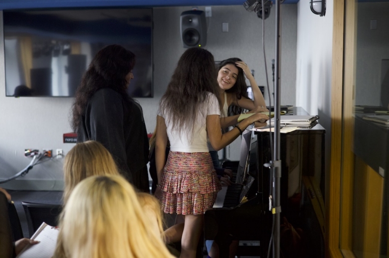 A group of Tisch Summer High School Recorded Music students stand around an upright piano in a classroom at the Clive Davis Institute of Recorded Music.